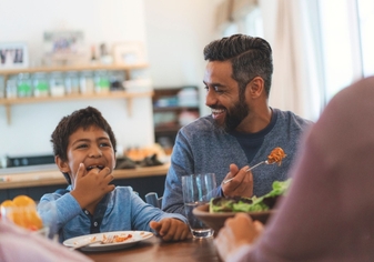 Dad and son eating dinner at table happy. 