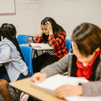 Child in a classroom with hands on head