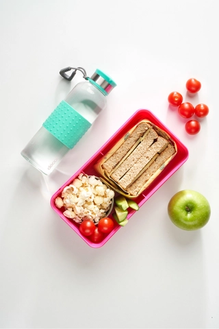Student desk scene with a lunchbox, water bottle and fruit