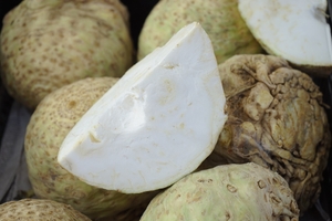 A cut wedge of celeriac ontop of four whole celeriac 